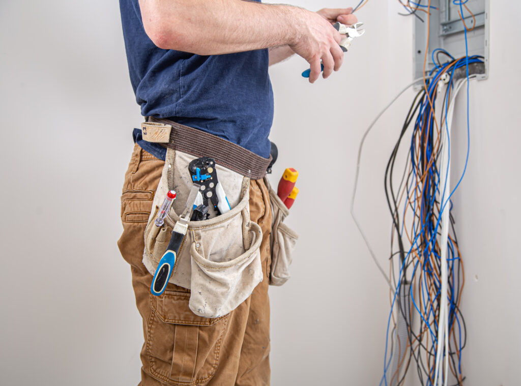 electrician builder examines the cable connection in the electrical line in switchboard indoor. electrician builder examines the cable connection in the electrical line in switchboard indoor.