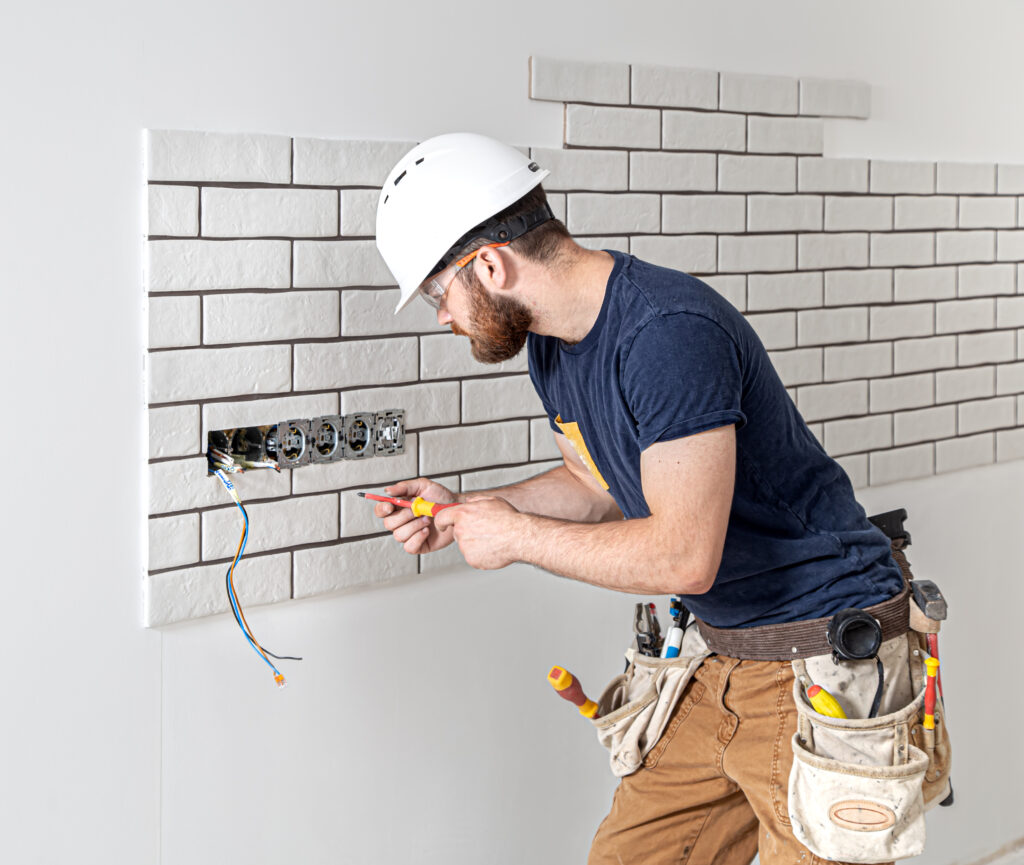 electrician builder in a white helmet at work, installation of sockets, and switches. electrician builder in a white helmet at work, installation of sockets, and switches.