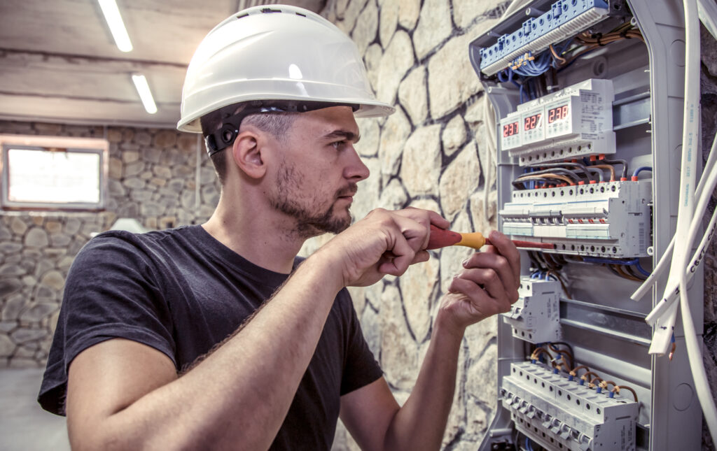a male electrician works in a switchboard with an electrical connecting cable a male electrician works in a switchboard with an electrical connecting cable